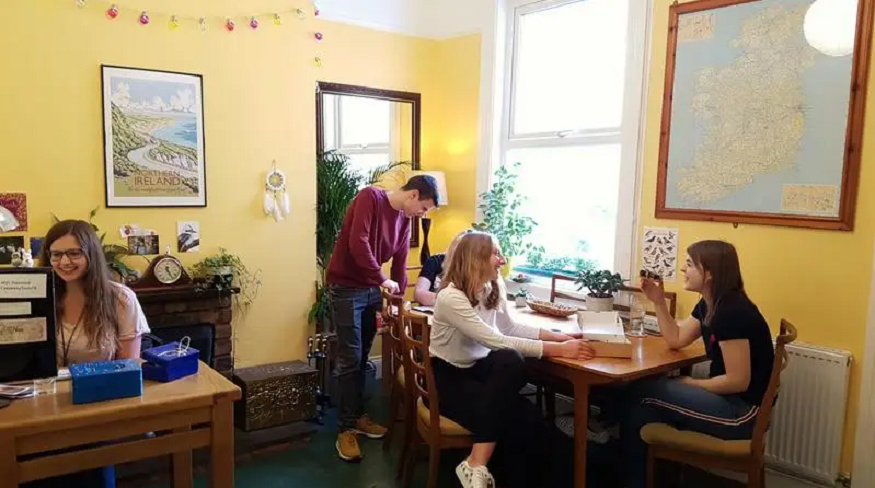 best hostels in belfast, people sitting a table in botanical backpackers hostel