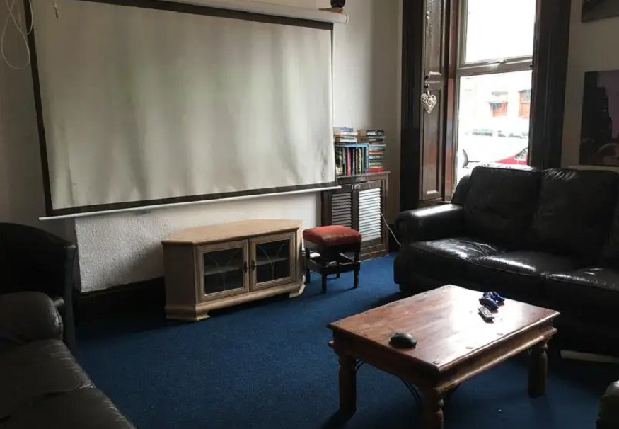 best hostels in belfast, lagain backpackers lounge area with sofas and projector